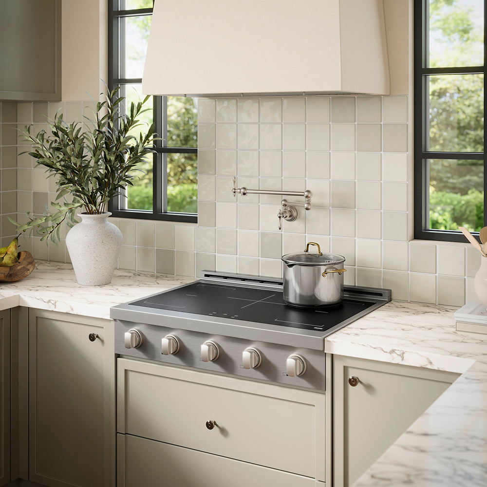 ZLINE 36 in. Paramount Induction Rangetop with 5 Element Cooktop in Stainless Steel (SINRT36) in a designer kitchen with tiled backsplash, light green cabinets, angled.
