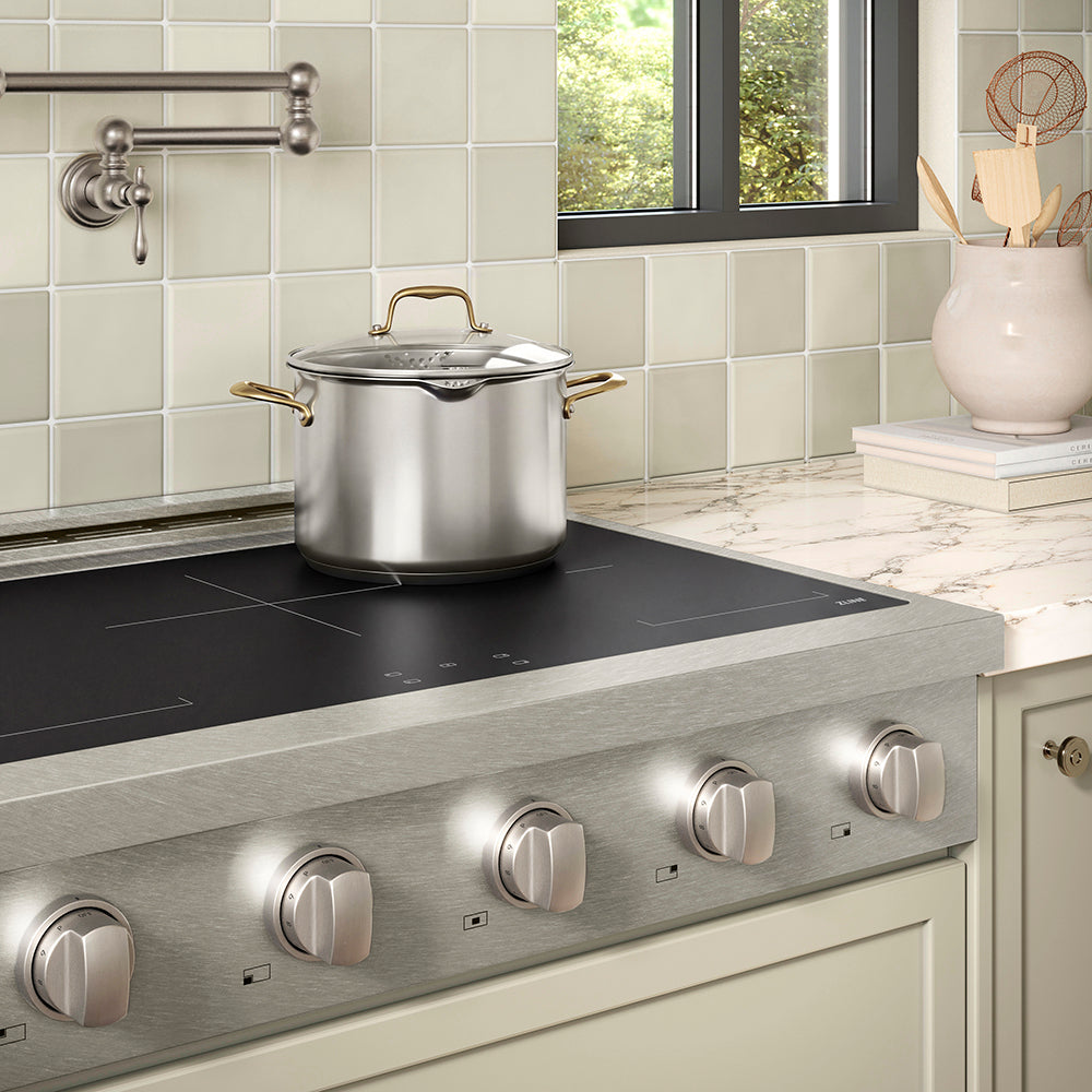 ZLINE 36 in. Paramount Induction Rangetop with 5 Element Cooktop in Satin Stainless Steel (SINRTS-36) in a designer kitchen with tiled backsplash, light green cabinets, angled.