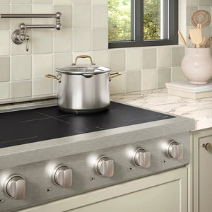 ZLINE 36 in. Paramount Induction Rangetop with 5 Element Cooktop in Satin Stainless Steel (SINRTS-36) in a designer kitchen with tiled backsplash, light green cabinets, angled.