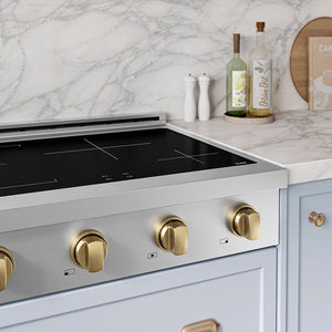 ZLINE Autograph Edition 30 in. Paramount Induction Rangetop with 4 Element Cooktop in Stainless Steel and Champagne Bronze Accents (SINRTZ-30-CB) in a designer kitchen with marble backsplash, light blue cabinets, angled.
