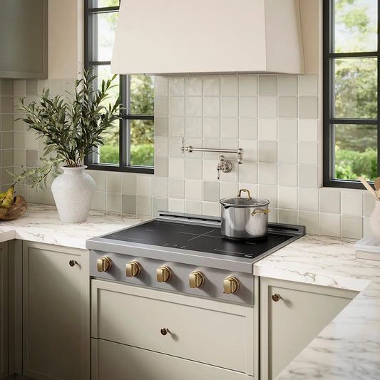 ZLINE Autograph Edition 36 in. Paramount Induction Rangetop with 5 Element Cooktop in Stainless Steel and Champagne Bronze Accents (SINRTZ-36-CB) in a designer kitchen with tiled backsplash, light green cabinets, angled.