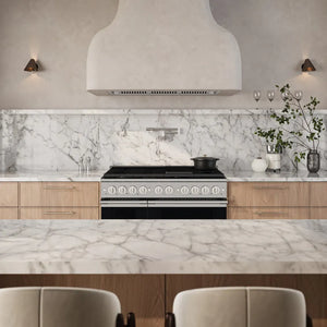 ZLINE 48 in. 6.7 cu. ft. Marino Double Oven Dual Fuel Range in Stainless Steel with 8 Brass Burners (MDR-BR-48) front, set in a modern kitchen with a large white range hood, white marble backsplash and island countertop, light wood cabinetry, and two chairs in the foreground.