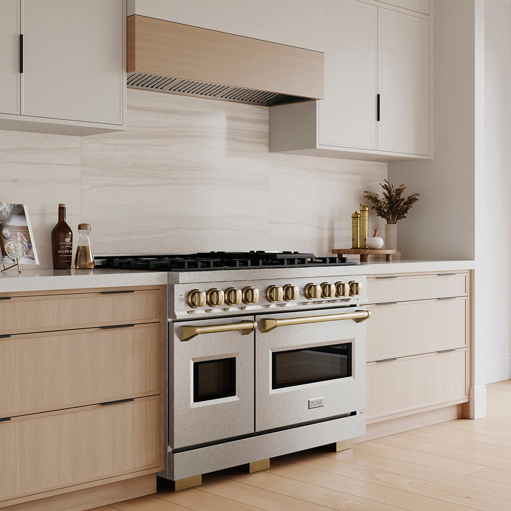 ZLINE Autograph Edition 48 in. 6.7 cu. ft. Classic Dual Fuel Range with 8 Burner DuoPro™ Cooktop and Dual Ovens in Satin Stainless Steel and Champagne Bronze Accents (PCDRSZ-48-CB) in a custom kitchen with wooden cabinets and white walls, side.