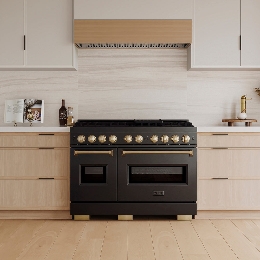 ZLINE Autograph Edition 48 in. 6.7 cu. ft. Classic Gas Range with 8 Burner DuoPro™ Cooktop and Dual Ovens in Black Stainless Steel and Champagne Bronze Accents (PCGRBZ-48-CB) in a custom kitchen with wooden cabinets and white walls, front.