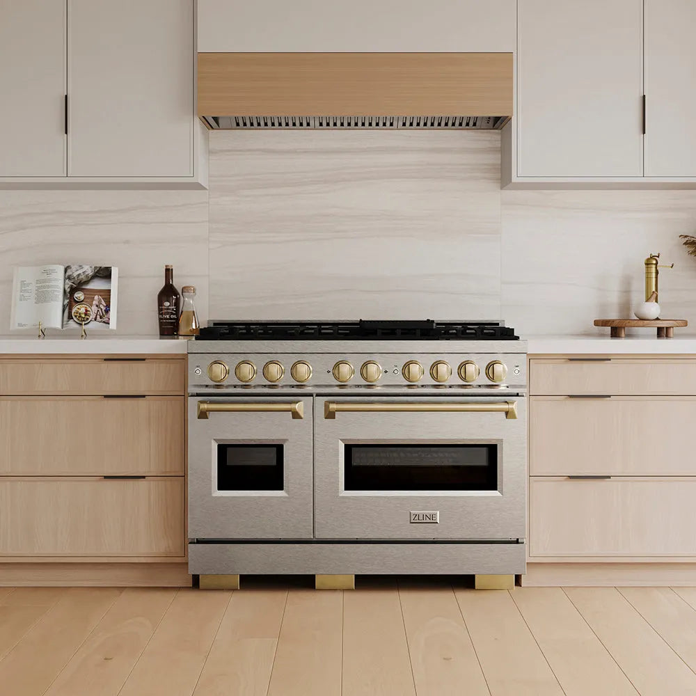 ZLINE Autograph Edition 48 in. 6.7 cu. ft. Classic Gas Range with 8 Burner DuoPro™ Cooktop and Dual Ovens in Satin Stainless Steel and Champagne Bronze Accents (PCGRSZ-48-CB) in a custom kitchen with wooden cabinets and white walls, front.