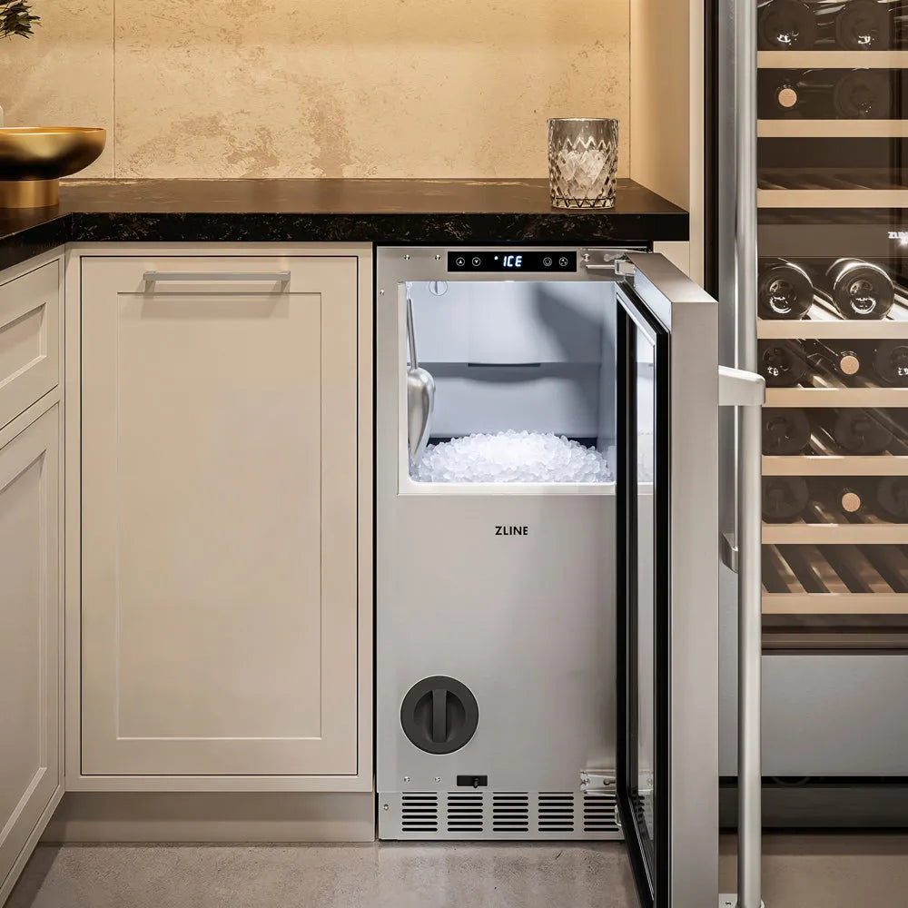 A ZLINE 15 in. Touchstone Nugget Ice Maker with Drain Pump and Solid Stainless Steel Door (INGD-ST-15), with its door open, showing nugget ice inside, set into a kitchen cabinetry unit next to a wine rack.