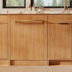 ZLINE Autograph Edition 24 in. Monument Series 3rd Rack Dishwasher with Auto Door Open Drying, 44dBa, Panel Ready with Polished Gold Handle (DWMTZ-24-G) front, in a kitchen with wooden cabinets and a window view.