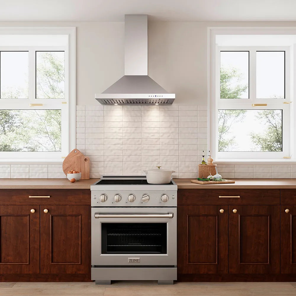 A stainless steel freestanding range with a matching ZLINE 30 in. Convertible Vent Wall Mount Range Hood in Stainless Steel (KB-30), set in a modern kitchen with dark wood cabinets, a white subway tile backsplash, and two windows.