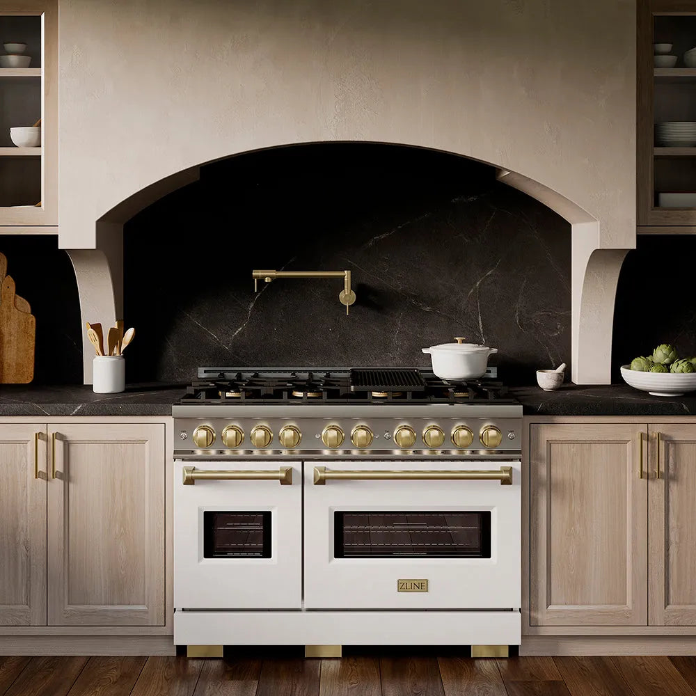ZLINE Autograph Edition 48 in. 6.7 cu. ft. Classic Dual Fuel Range with 8 Burner DuoPro™ Cooktop and Dual Ovens with White Matte Doors and Champagne Bronze Accents (PCDRZ-WM-48-CB) in a custom kitchen with marble backsplash and large range hood, front.