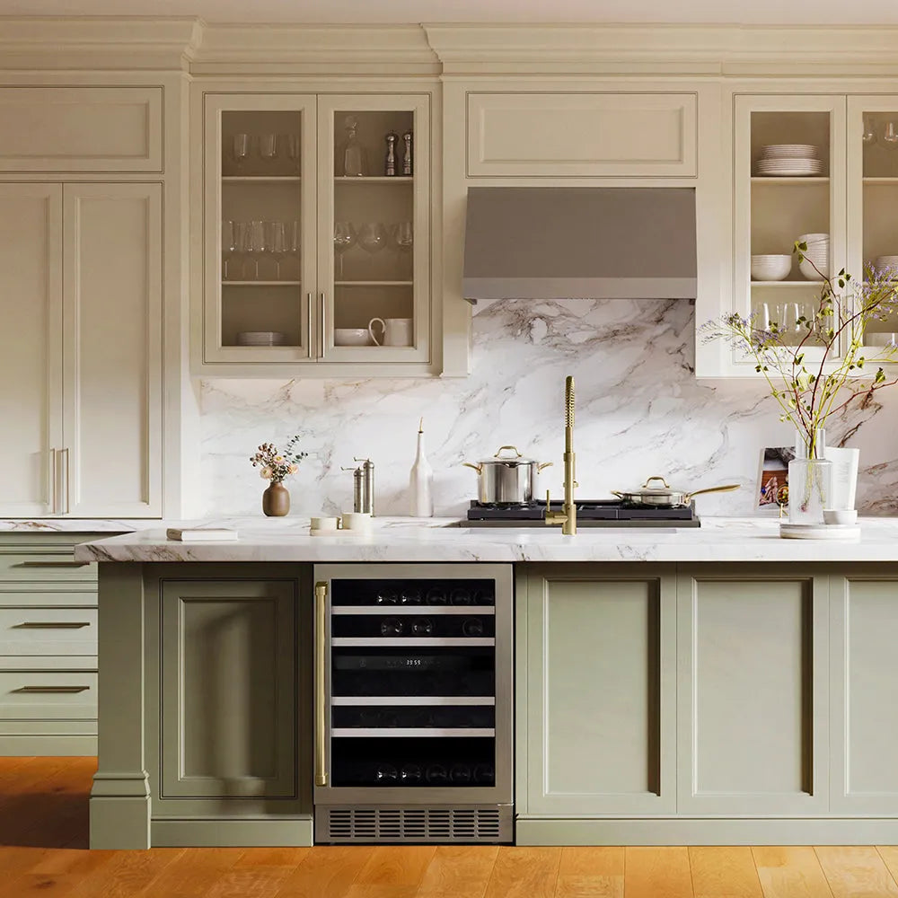 ZLINE Autograph Edition 24 in. Monument Dual Zone 44 Bottle Wine Cooler in Stainless Steel with Champagne Bronze Accents (RWVZ-UD-24-CB) in a kitchen with a marble backsplash, stainless steel appliances, and light wood cabinets.