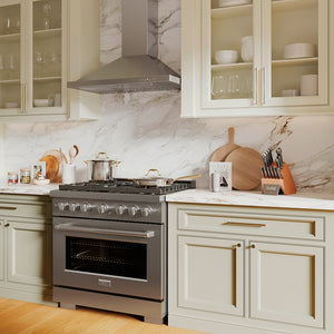 ZLINE 36 in. Convertible Vent Wall Mount Range Hood in Stainless Steel (KB-36) in a kitchen with stainless steel oven, marble countertop, and light-colored cabinets.