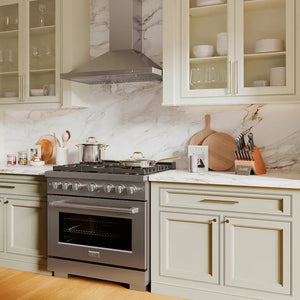 ZLINE 36 in. Convertible Vent Wall Mount Range Hood in Stainless Steel (KB-36) in a kitchen with stainless steel oven, marble countertop, and light-colored cabinets.
