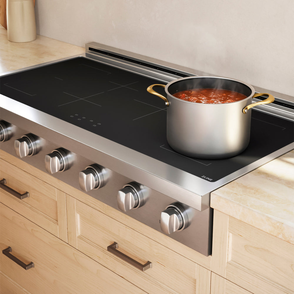 A ZLINE 48 in. Paramount Induction Rangetop with 7 Element Cooktop in Stainless Steel (SINRT48), with a large silver pot of stew on the cooktop, set in a kitchen with light wood cabinets.