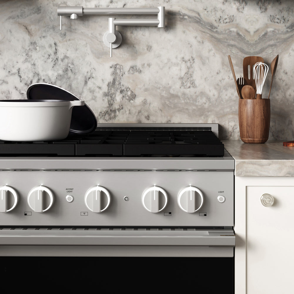 ZLINE 30 in. 4.2 cu. ft. Marino Dual Fuel Range with Gas Cooktop and Electric Convection Oven in Stainless Steel with 4 Brass Burners (MDR-BR-30) front close-up, set in a modern kitchen with marble countertops. A white pot sits on the cooktop, and a wooden utensil holder is on the counter.