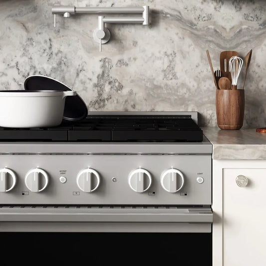 ZLINE 30 in. 4.2 cu. ft. Marino Gas Range with Convection Gas Oven in Stainless Steel with 4 Brass Burners (MGR-BR-30) front close-up, set in a modern kitchen with marble countertops. A white pot sits on the cooktop, and a wooden utensil holder is on the counter.