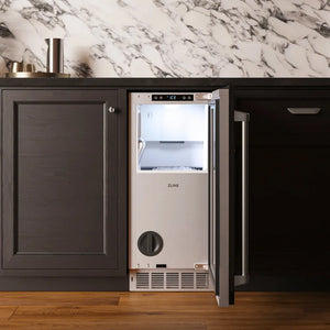 ZLINE 15 in. Touchstone Nugget Ice Maker with Drain Pump and Panel-Ready Door (INGDP-15) with its door open, set into a kitchen cabinet with a dark countertop and marble backsplash.