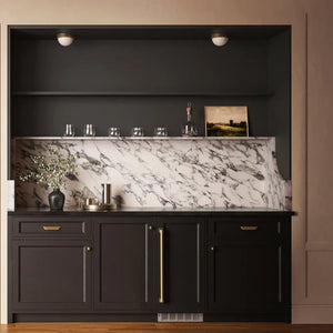 ZLINE Autograph Edition 15 in. Touchstone Nugget Ice Maker with Drain Pump and Panel-Ready Door with Champagne Bronze Handle (INGDPZ-15-CB) in a modern built-in bar cabinet, styled with glassware, a vase of flowers, and a small framed picture.