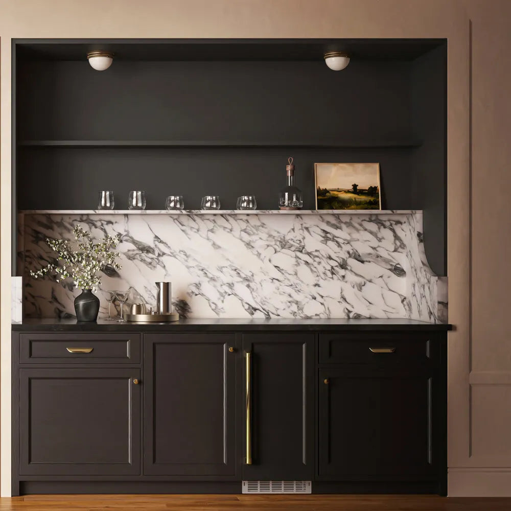 ZLINE Autograph Edition 15 in. Touchstone Nugget Ice Maker with Drain Pump and Panel-Ready Door with Polished Gold Handle (INGDPZ-15-G) in a modern built-in bar cabinet, styled with glassware, a vase of flowers, and a small framed picture.