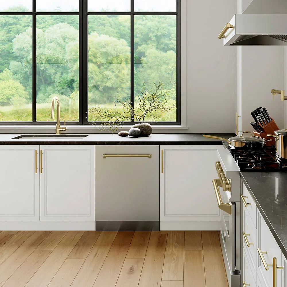 Modern kitchen with white cabinets, ZLINE Autograph Edition 24 in. Tallac Series 3rd Rack Top Control Built-In Tall Tub Dishwasher in Stainless Steel with Champagne Bronze Handle, 51dBa (DWVZ-304-24-CB), and a view of greenery outside.