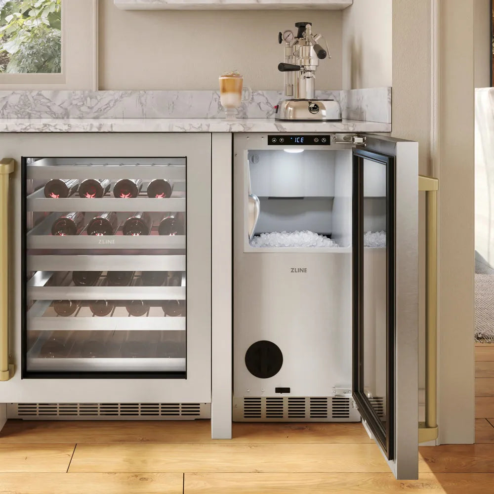A ZLINE Autograph Edition 15 in. Touchstone Nugget Ice Maker with Drain Pump and Solid Stainless Steel Door with Champagne Bronze Handle (INGDZ-ST-15-CB) under a marble countertop, with the door open to show ice inside.