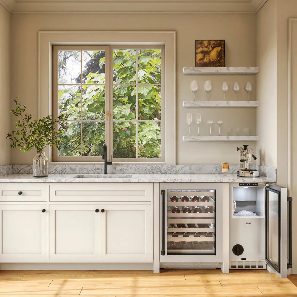 A built-in wine refrigerator and ZLINE Autograph Edition 15 in. Touchstone Nugget Ice Maker with Drain Pump and Solid Stainless Steel Door with Matte Black Handle (INGDZ-ST-15-MB), with marble countertops in a modern kitchen setting with a window showing green foliage outside.