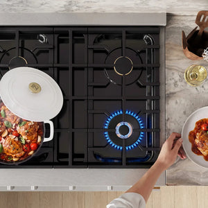 ZLINE 30 in. 4.2 cu. ft. Marino Dual Fuel Range with Gas Cooktop and Electric Convection Oven in Satin Stainless Steel with 4 Brass Burners (MDRS-BR-30) top-down, above cooktop. A white-lidded pot with a colorful food mixture sits on the left burner, while a blue gas flame burns under a pan on the front-right burner.