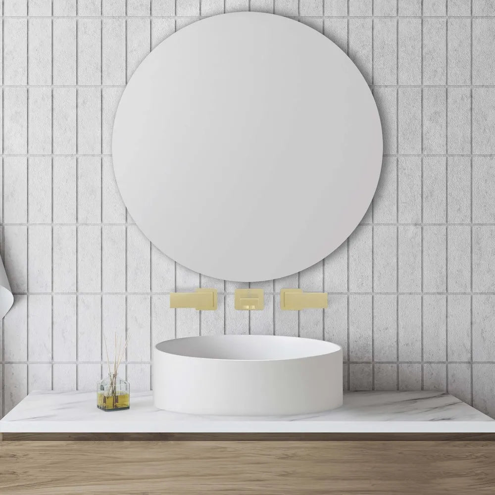 ZLINE Autograph Edition Bliss Wall Mount Bath Faucet in Polished Gold (BLS-BFW-PG) in a bathroom with a round mirror, sink, and towels on a tiled wall.