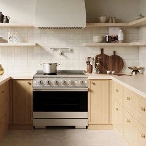 A ZLINE 36 in. 5.2 cu. ft. Marino Induction Range with 5 Element Cooktop and Electric Convection Oven in Stainless Steel (MINR36) installed in a modern kitchen with light wood cabinets, beige countertops, and a tiled backsplash.
