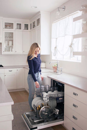 Woman using a ZLINE 24 in. Tallac Series 3rd Rack Tall Tub Dishwasher in Custom Panel Ready with Stainless Steel Tub, 51dBa (DWV-24) in a farmhouse kitchen