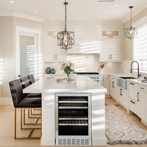 Modern kitchen with white island featuring a ZLINE Autograph Edition 24 in. Monument Dual Zone 44 Bottle Wine Cooler in Stainless Steel with Champagne Bronze Accents (RWVZ-UD-24-CB), black chairs, and decorative elements.
