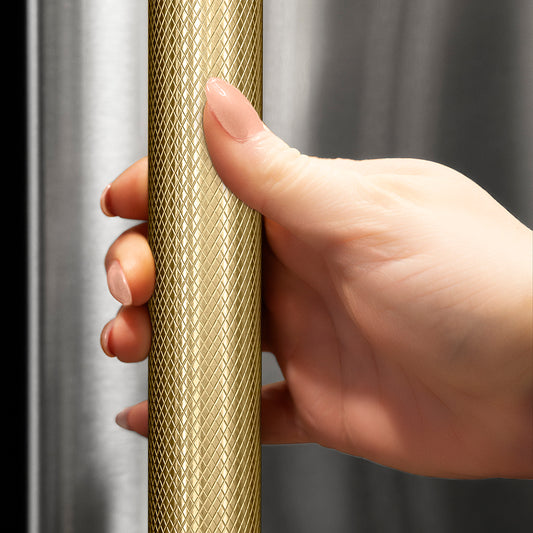 ZLINE Autograph Edition 15 in. Touchstone Clear Cube Ice Maker with Drain Pump and Solid Stainless Steel Door with Champagne Bronze Helix Handle (ICCDZ-ST-15-KCB) hand holding Helix handle showing knurled diamond texture.