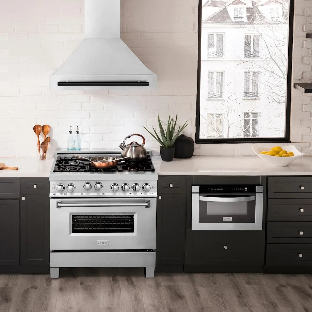 Modern kitchen with ZLINE Autograph Edition 36 in. Satin Stainless Steel Wall Mount Range Hood with Matte Black Handle (8654SNZ-36-MB), stainless steel range, black cabinets, and white countertops.