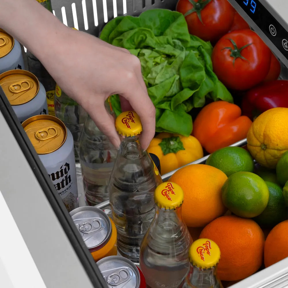 Hand reaching into a ZLINE 24 in. Touchstone 168 Can Outdoor-Rated Dual Refrigerator Drawer with White Matte Doors (RDSO-WM-24) filled with drinks, fruits, and vegetables.
