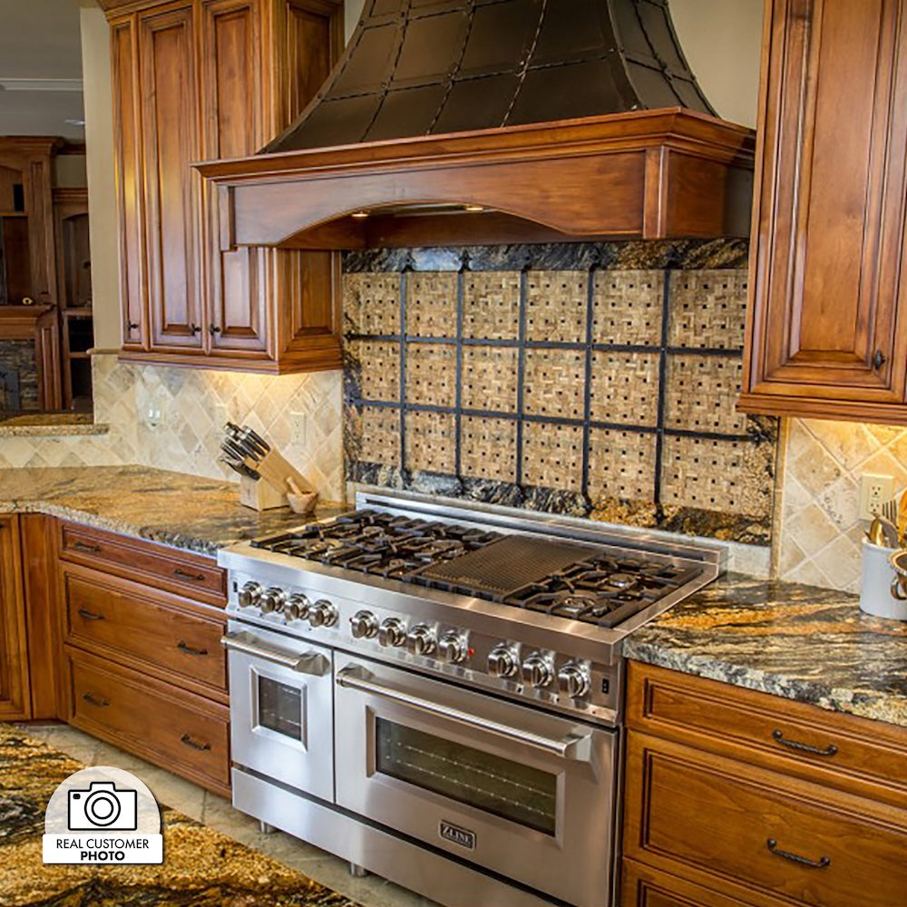Stainless steel range in a kitchen with wooden cabinets, decorative backsplash, and a custom rustic range hood using a ZLINE 46 in. Ducted Wall Mount Range Hood Insert in Stainless Steel (698-46).