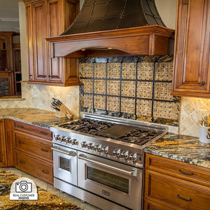 Stainless steel range in a kitchen with wooden cabinets, decorative backsplash, and a custom rustic range hood using a ZLINE 46 in. Ducted Wall Mount Range Hood Insert in Stainless Steel (698-46).