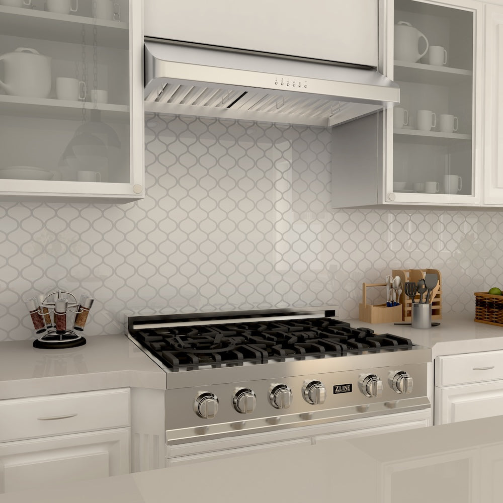 ZLINE 36 in. Ducted Under Cabinet Range Hood in Stainless Steel (623-36) above a stainless steel gas cooktop in a farmhouse kitchen with white cabinets and backsplash.