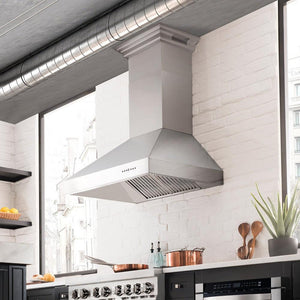 ZLINE Professional Wall Mount Range Hood in Stainless Steel with Built-in ZLINE CrownSound Bluetooth Speakers (697CRN-BT) in a luxury kitchen with matching range and microwave, side.