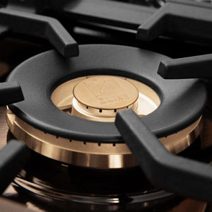 ZLINE brass burners on black porcelain cooktop with cast-iron grates.